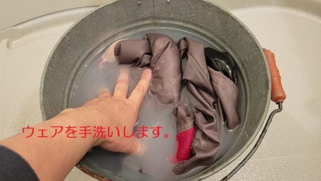 「TECH WASH」を入れたバケツで、古いウェアを手洗いしている写真