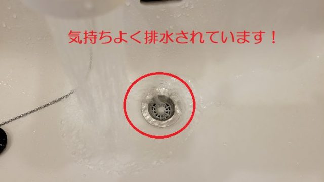 ワイヤータイプの排水管クリーナーを使って排水パイプから取り除いた洗面台に水を流して、排水力が戻ったことを説明した写真。